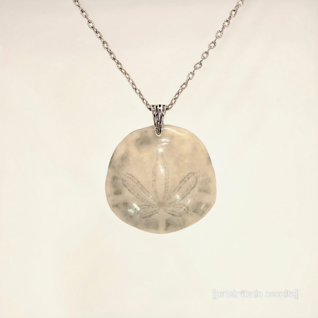 Necklace with a round pendant featuring a leaf design on a light beige background
