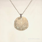 Necklace with a round pendant featuring a leaf design on a light beige background