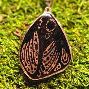 Bronze pendant with intricate design on a moss background