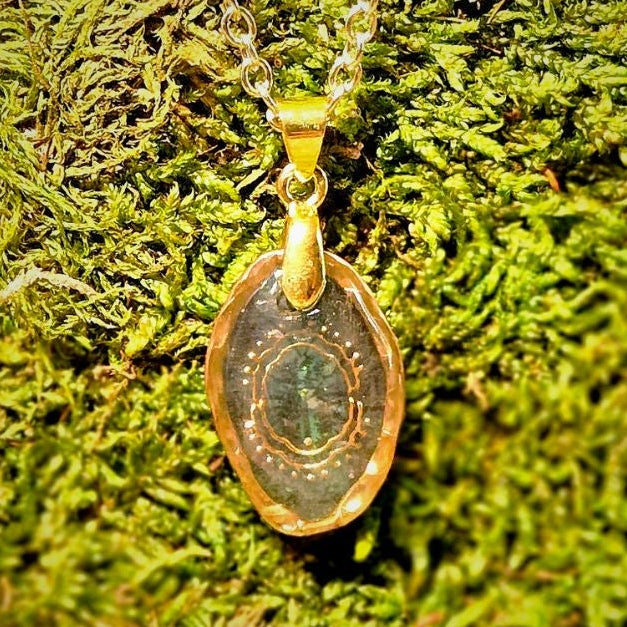 Gold necklace with a pendant on a green moss background