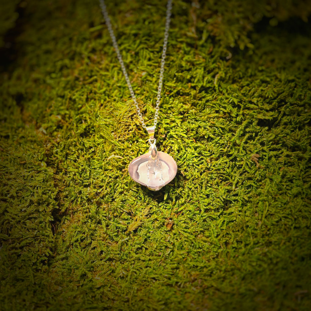 Silver necklace with a pendant on a green moss background