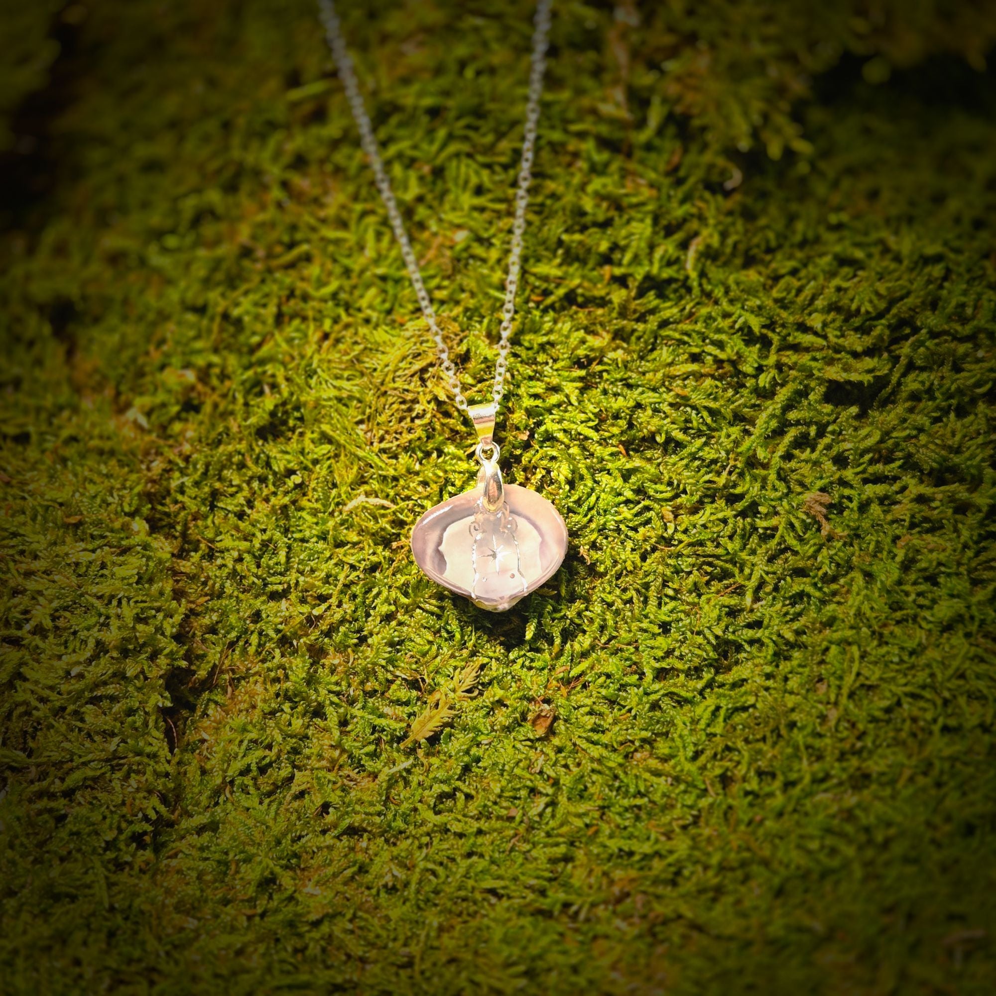 Silver necklace with a pendant on a green moss background