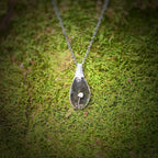 Necklace with a pendant on a mossy surface