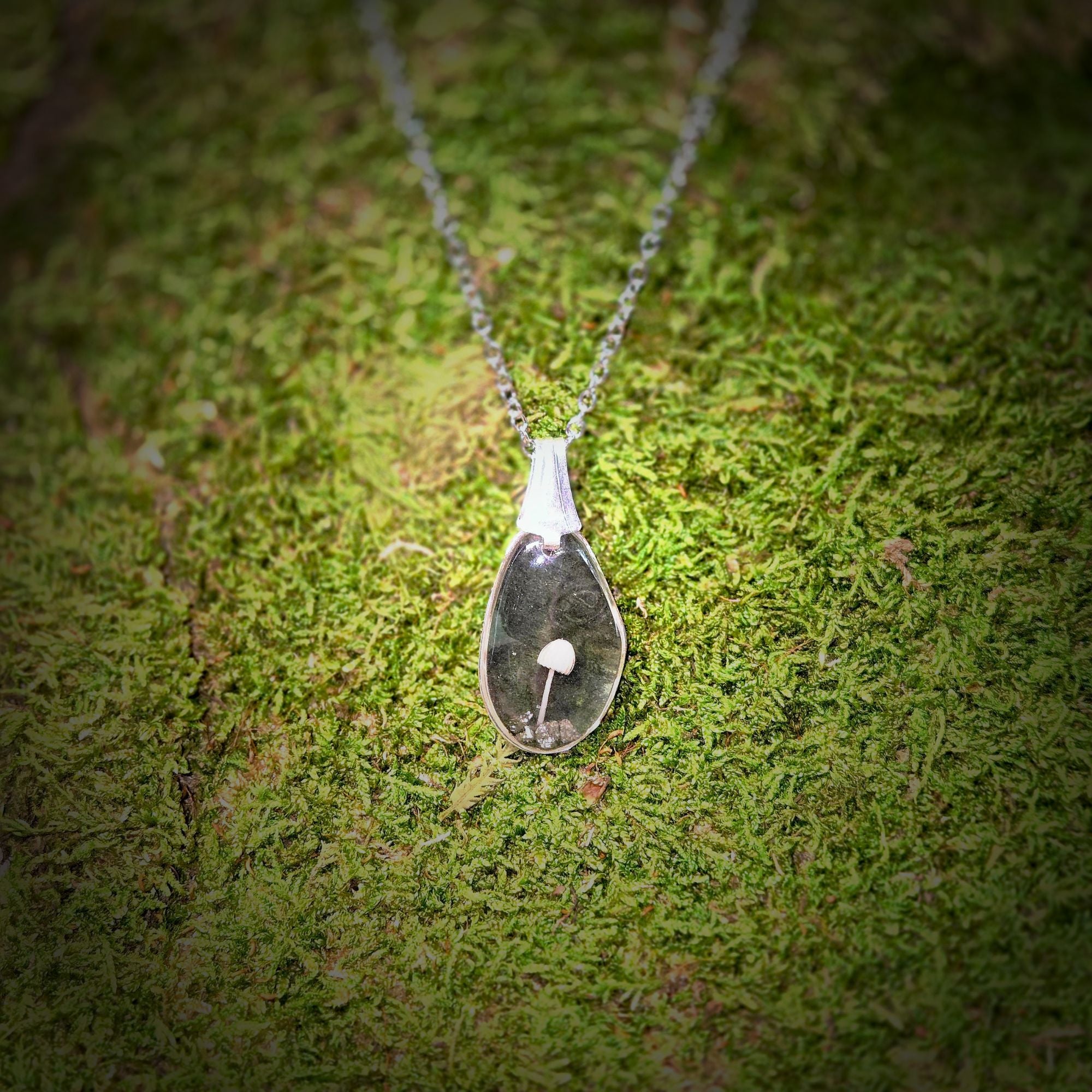 Necklace with a pendant on a mossy surface