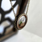 Necklace with a round pendant featuring a natural scene on a blurred background