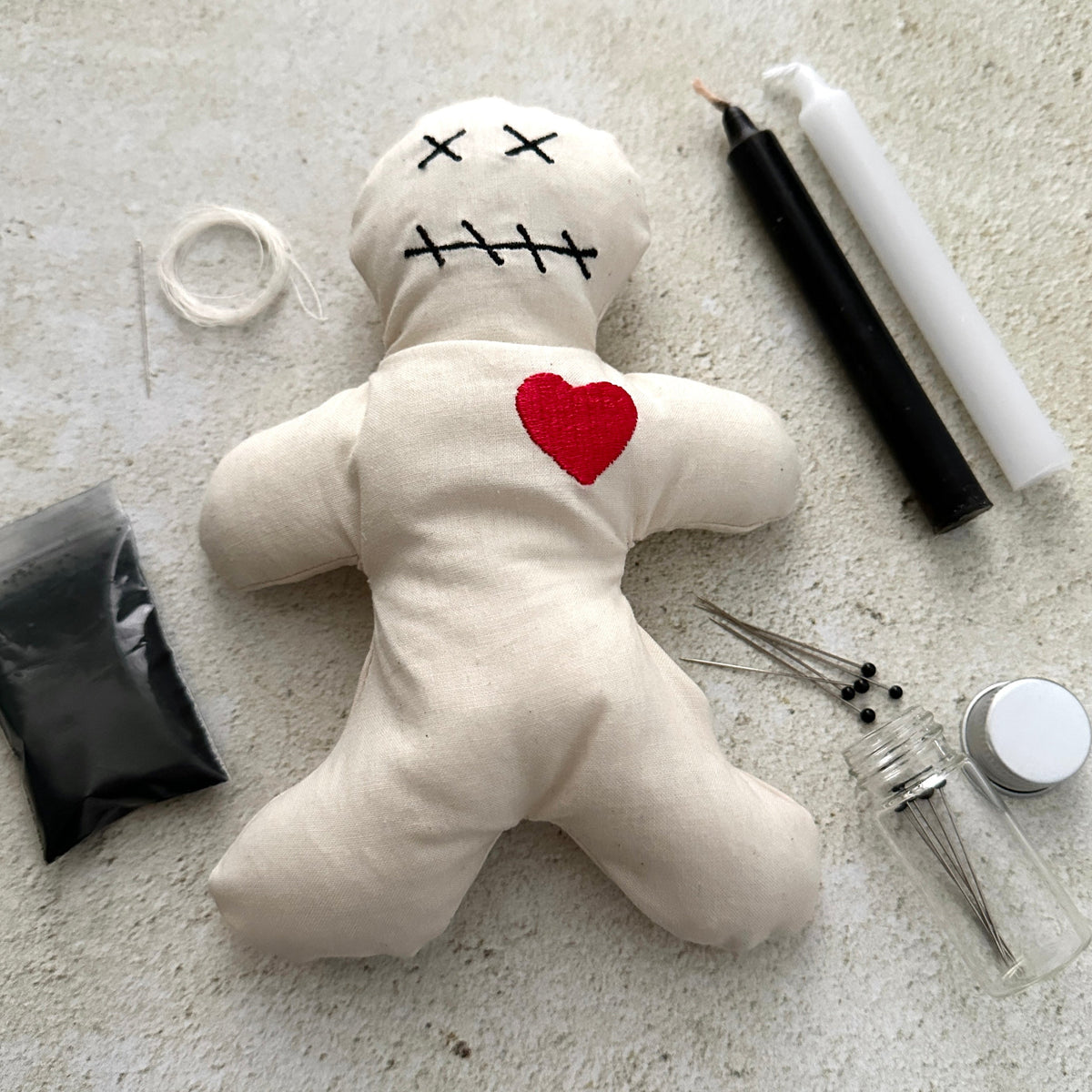 Voodoo doll with a red heart on a light surface with卜算子 tools.