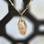 A faceted clear resin pendant containing a soft pink flower inclusion, hanging from a 19‑inch gold‑tone chain.