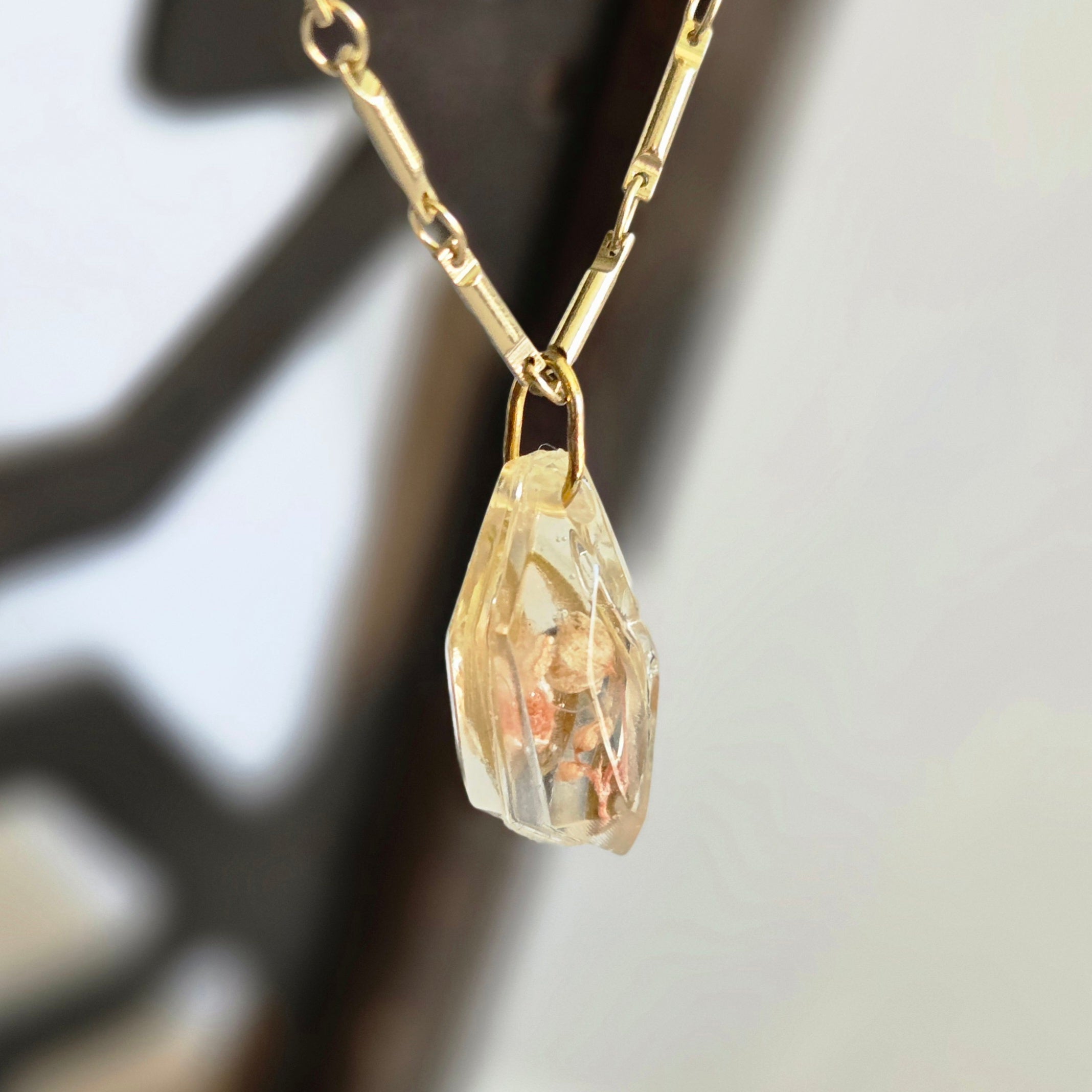 Gold necklace with a unique pendant on a blurred background