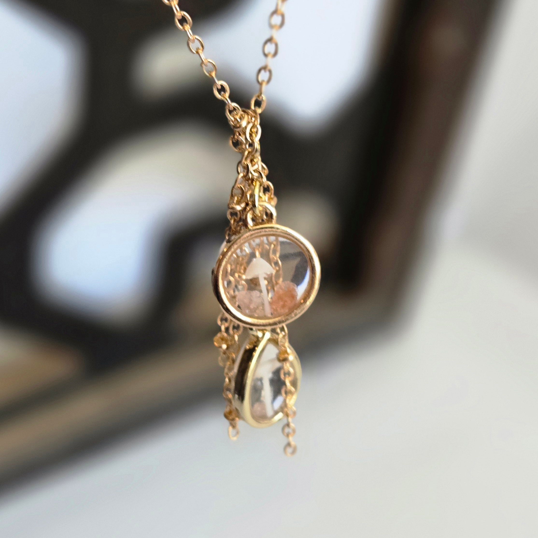 Gold necklace with a round pendant featuring a cat illustration on a blurred background
