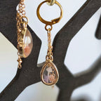A pair of gold‑tone teardrop earrings containing tiny mushrooms and botanical elements suspended in clear resin.