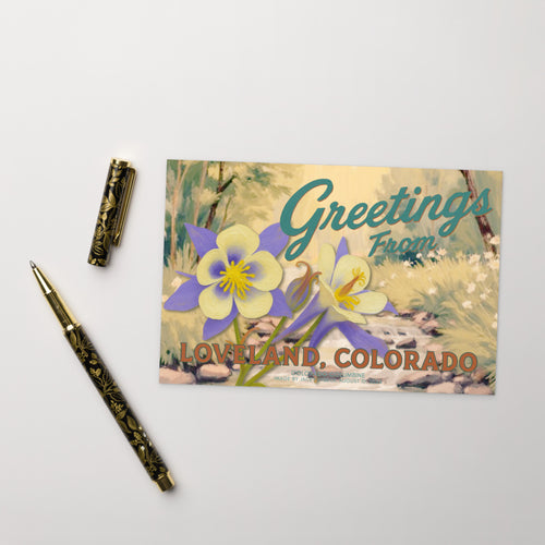 Postcard with floral design and text 'Greetings from Loveland, Colorado' on a white background with a pen. Beauty Undiscovered