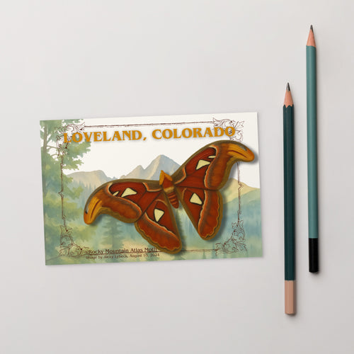 Postcard with butterfly design and 'Loveland, Colorado' text on a gray background with a pencil.  Beauty Undiscovered